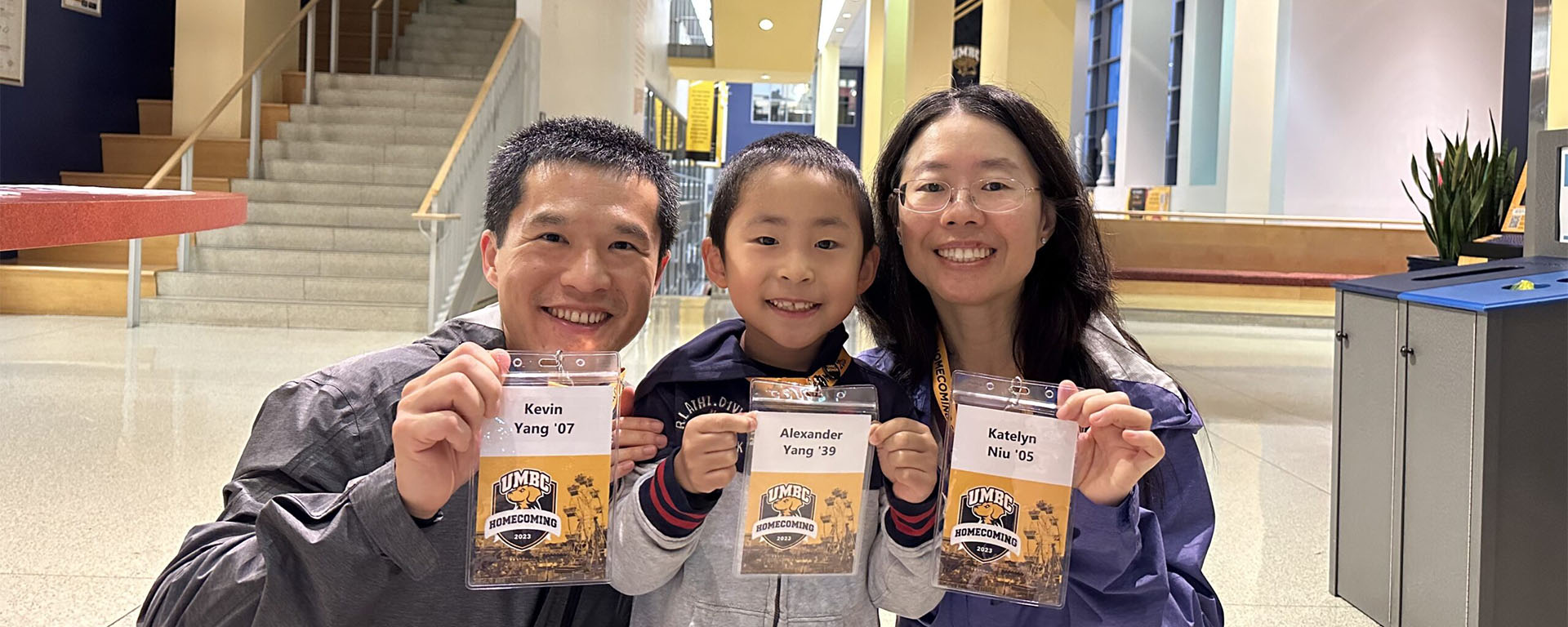 Kevin Yang '07, Katelyn Niu '05, and their son holding up their Homecoming 2023 nametags.