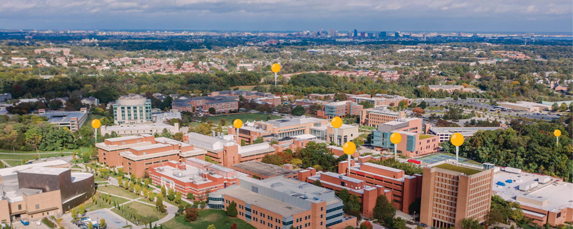 UMBC's campus from a bird's eye view, with gold location pegs superimposed the image to indicate research zones