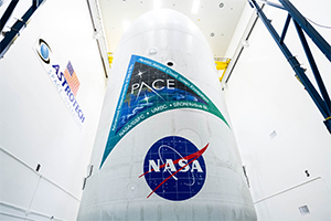 large vertical white cylinder inside a large white room, labeled with "PACE,";"NASA,";"UMBC"]; and "SRON/Airbus NL"