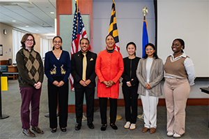 Six UMBC college students gather around Cheryl R. Campbell, the assistant secretary for administration for HHS at a press conference.