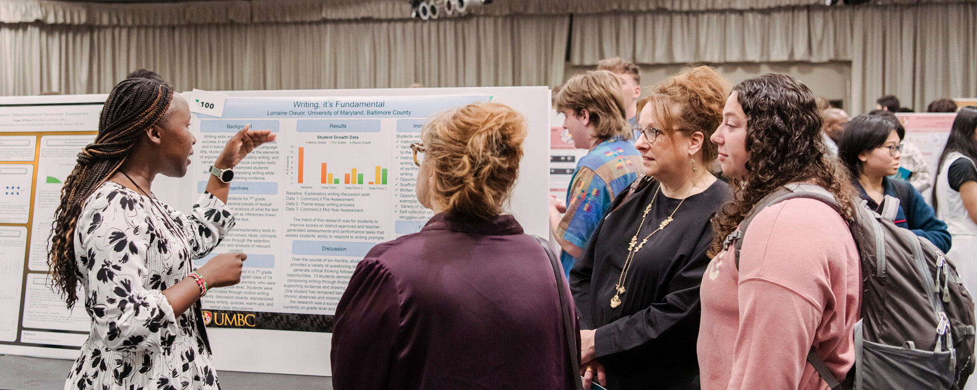 People standing near a poster board presenting research at UMBC's 2024 Undergraduate Research and Creative Achievement Day in 2024.
