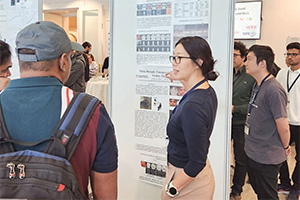 Woman stands near research poster, talks to other people.