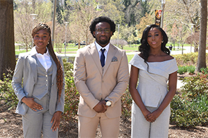 three well-dressed students stand outdoors
