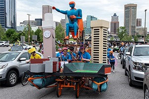 IMAGE Man portrayed a Baltimore superhero flying over the City to celebrate power and resilience of individuals with disabilities, and who plays sports. On the left is the Bromo Seltzer tower. On the right is the Inner Harbor World Trade Center—on both the sculpture and full-size in real life.