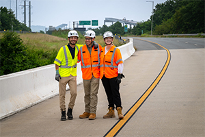 three people standing near a bridge wearing safety equipment