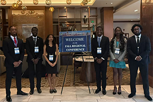 a group of students stand with a sign announcing the 2025 fall regional conference of the National Society of Black Engineers