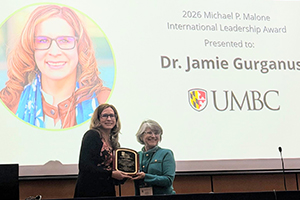 Gurganus accepts plaque on stage at APLU
